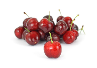 Single red cherry in front of group of cherries