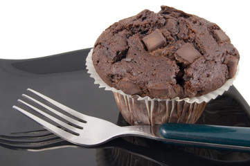 whole chocolate muffin with fork on plate