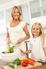Mother & Daughter Preparing Salad In Modern Kitchen