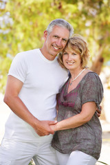Fototapeta premium Mature couple smiling and embracing. Focus on the woman.