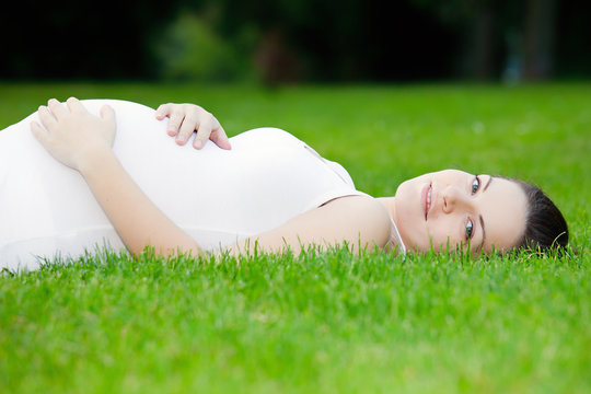 Beautiful pregnant woman laying on grass