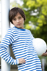 Junge lehnt am Torpfosten