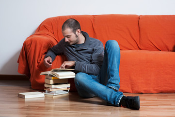 uomo seduto sul divano arancione che legge libro