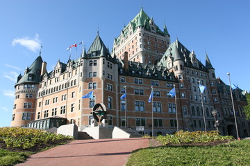 Fototapeta premium Frontal Fassade of Four-Stars-Hotel Fairmont Château Frontenac in Quebec City, Canada. UNESCO monument and flags in the foreground