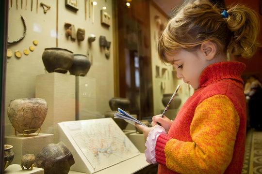 little girl writes to writing-books at excursion in museum