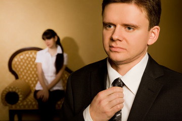 businessman in suit correcting tie and beautiful young  brunette