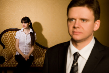 businessman in suit and beautiful young woman sitting on sofa