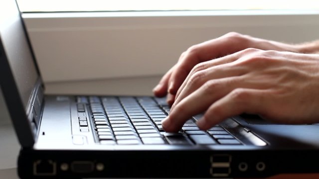 Hands typing on laptop keyboard