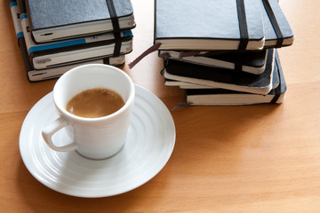 Espresso neben Stapel von Notizbüchern, Tagebüchern - 23256919