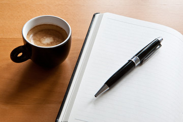 schwarze Tasse mit Espresso und Tagebuch