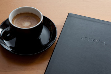 schwarze Tasse mit Espresso und Tagebuch