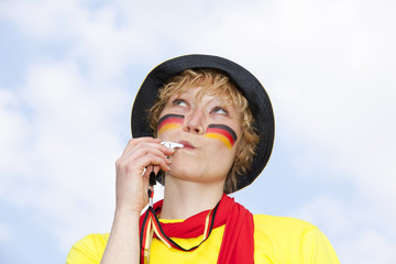 weiblicher Deutschlandfan mit Trillerpfeife schaut nach oben