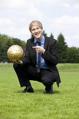 lächelnder Geschäftsmann zeigt auf Fussball