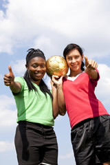 zwei lächelnde Fussballspielerinnen zeigen Daumen hoch
