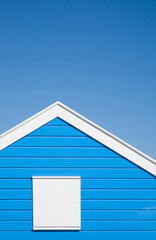bright blue colored; beach hut with white trim; under blue sky