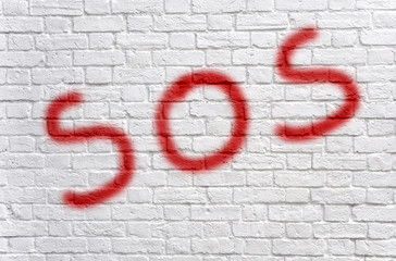 SOS graffiti on a white brick wall