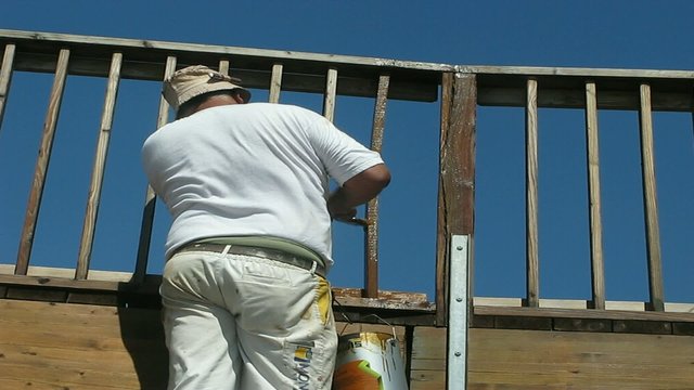 PINTOR BARNIZANDO LA BARANDILLA DE MADERA DE UN PUENTE