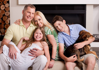 Fototapeta na wymiar Happy domestic family sitting in living room with dog