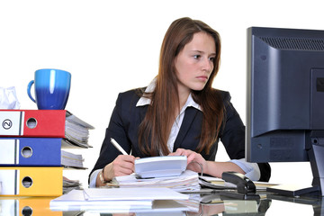 Junge Frau arbeitet im Büro zwischen Akten und PC