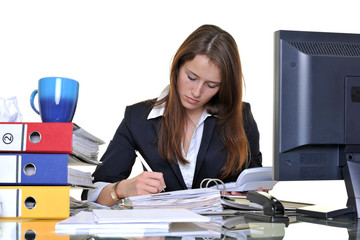 Junge Frau arbeitet im Büro zwischen Akten und PC