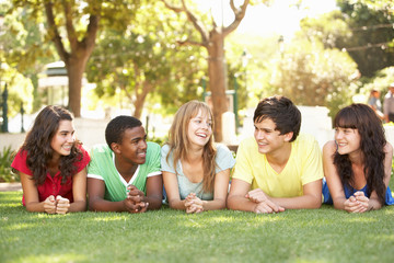 Fototapeta na wymiar Group Of Teenagers Lying On Stomachs In Park