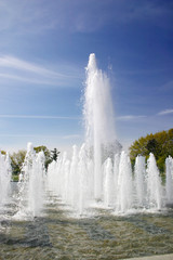 A water fountain in the garden with blue background.