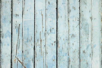 Old weathered light blue painted fence close up.