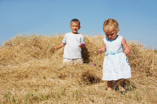 two kids playing in hay