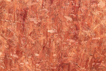 Orange coated recycled oriented strand board close up.