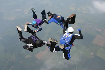 Tuinposter Four skydivers form a circle while in freefall © Joggie Botma