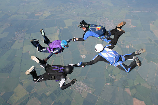 Four skydivers in freefall holding hands