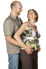 Portrait of happy pregnant couple looking at eachother smiling.
