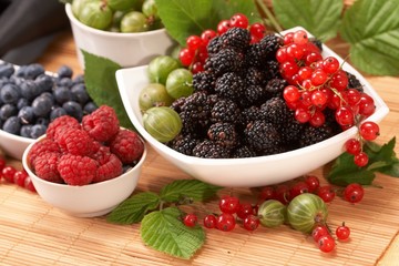 Berries in plates, on a table, among green leaves