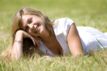 jeune femme blonde souriante allongée dans l'herbe