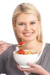 Young Woman Eating Bowl Of Healthy Breakfast Cereal In Studio