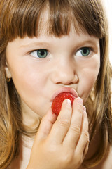 Portrait of beautiful little girl eating tasty strawberry