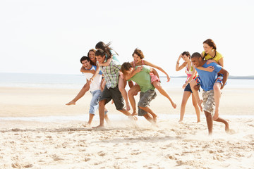 Group Of Friends Running Along Beach Together