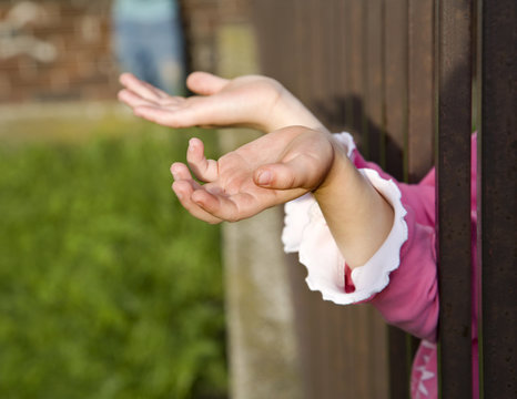 hands of little girl and metal fence