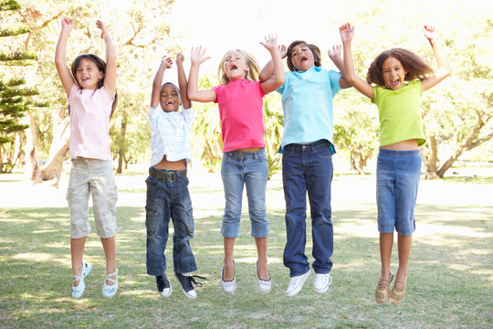 Group Of Children Jumping In Air In Park