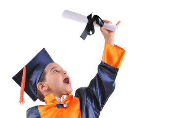 Elementary boy wearing graduation cap and gown shows his diploma