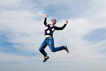 Fototapeta premium young man in the eyeglasses jumping in clouds