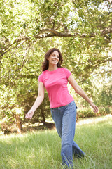 Naklejka premium Young Woman Walking Through Long Grass In Park