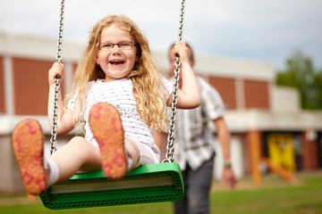 Mädchen schaukelt auf Spielplatz