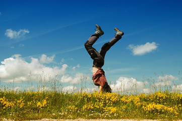 Young woman doing a cartwheel in a meadow