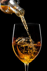 White wine poured in a glass isolated on a black  background