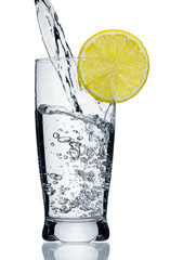 Water flowing in a glass with a lemon segment