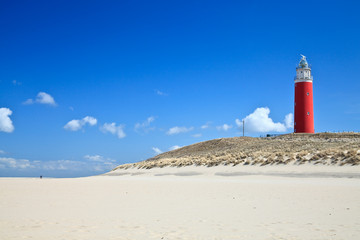 Lighthouse in the dunes at the beach - obrazy, fototapety, plakaty