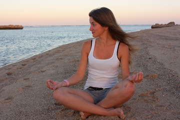 Fototapeta na wymiar young woman practicing yoga at the beach