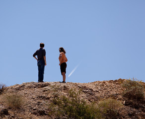 Hikers in desert point to aircraft trail