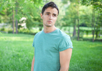 Portrait of a handsome young man while outdoors in a park on a l